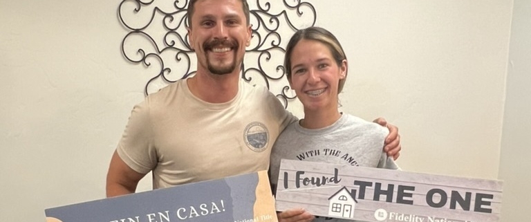 first time home buyers standing with signs after a successful closing