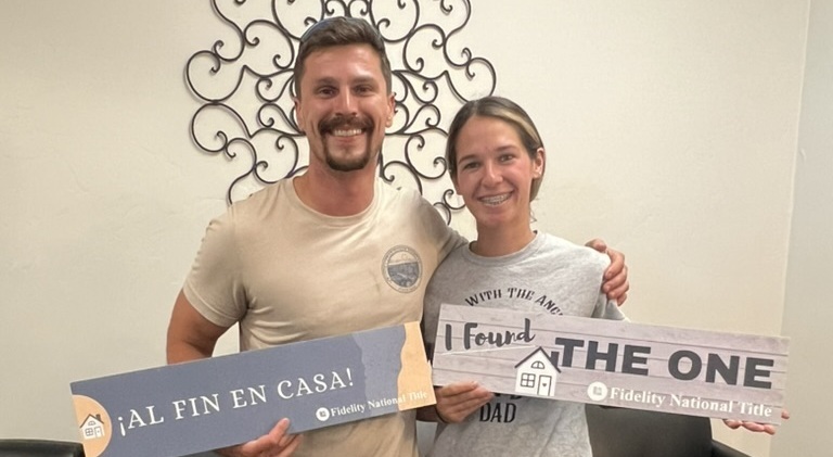 first time home buyers standing with signs after a successful closing