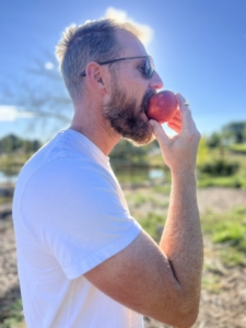 Oliver eating a peach right off the tree out in the orchard