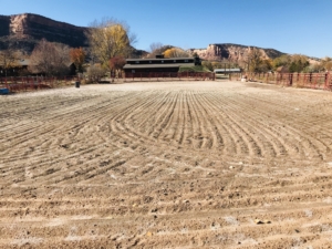 empty plowed farm field with house in the background